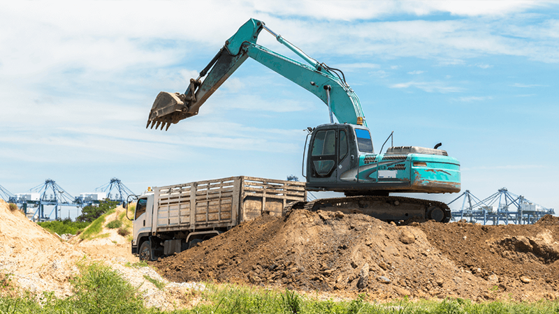 An Excavator Loads A Truck With Excavated Soil At A Construction Site Png