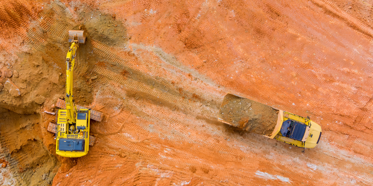 Excavator loading soil into a dump truck at a construction site