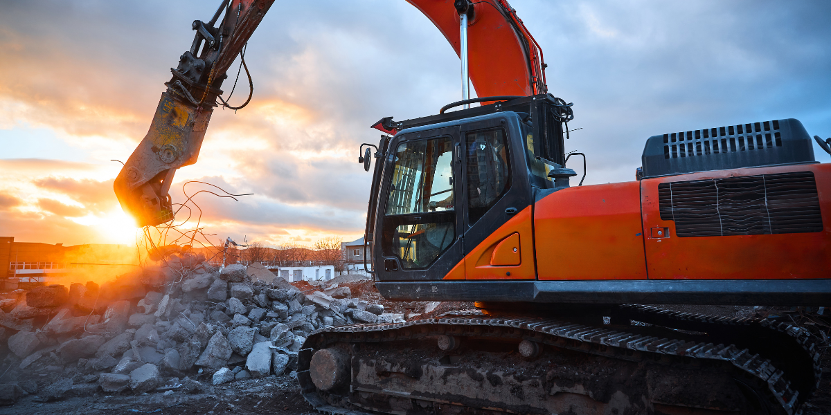 Excavator clearing concrete rubble at a demolition site