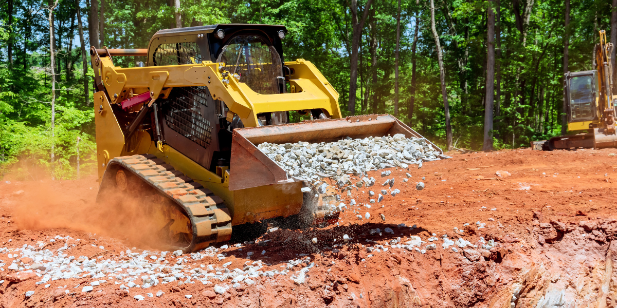 Skid steer spreading crushed stone on a construction site