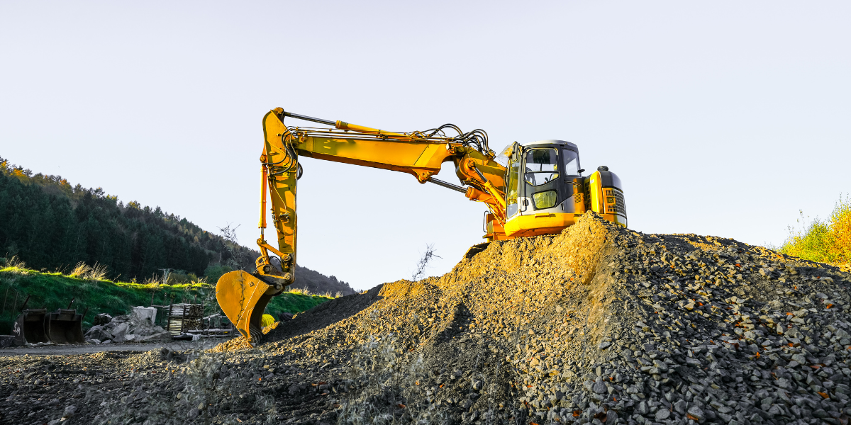 Yellow excavator working on a pile of gravel at a construction site